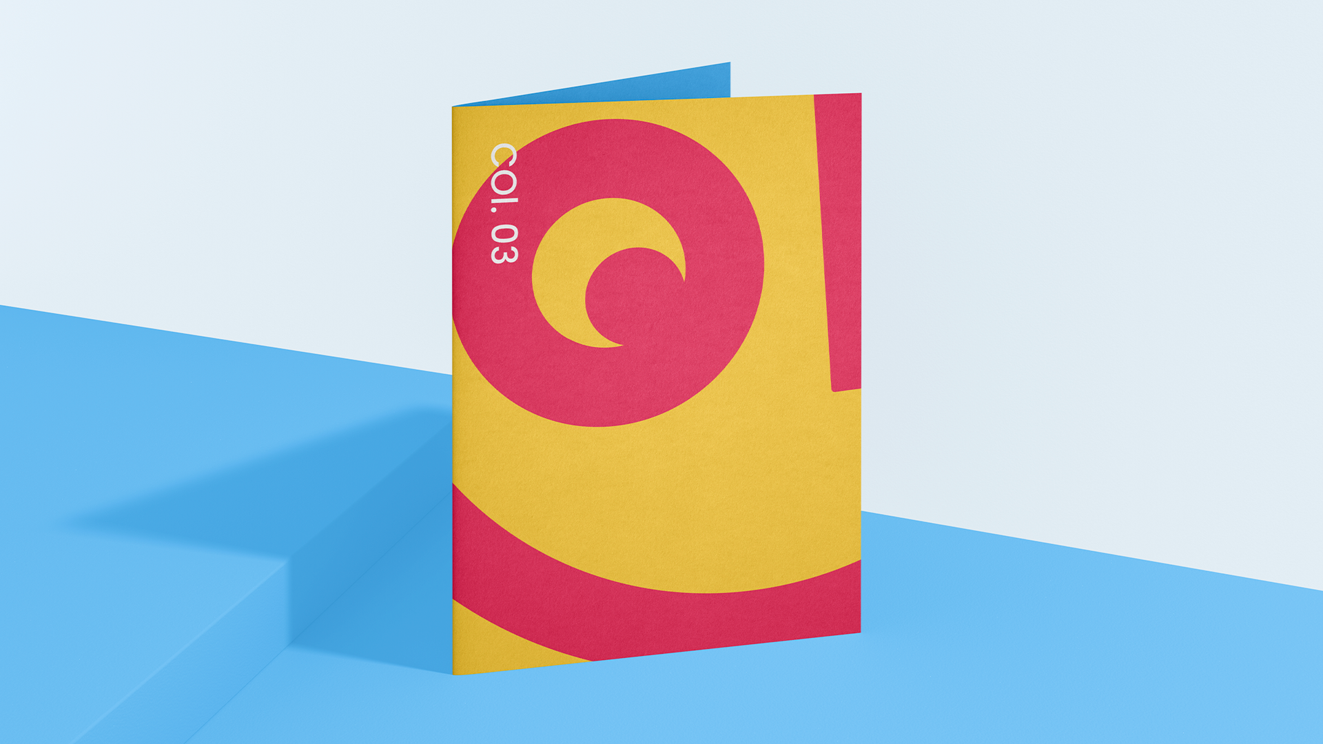 Um livro amarelo e vermelho com uma espiral na capa está sobre uma superfície azul.