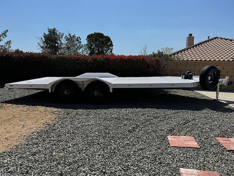 A Flatbed Car Trailer is parked on gravel in front of a house