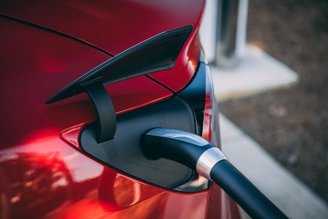 A red electric car is being charged at a charging station.