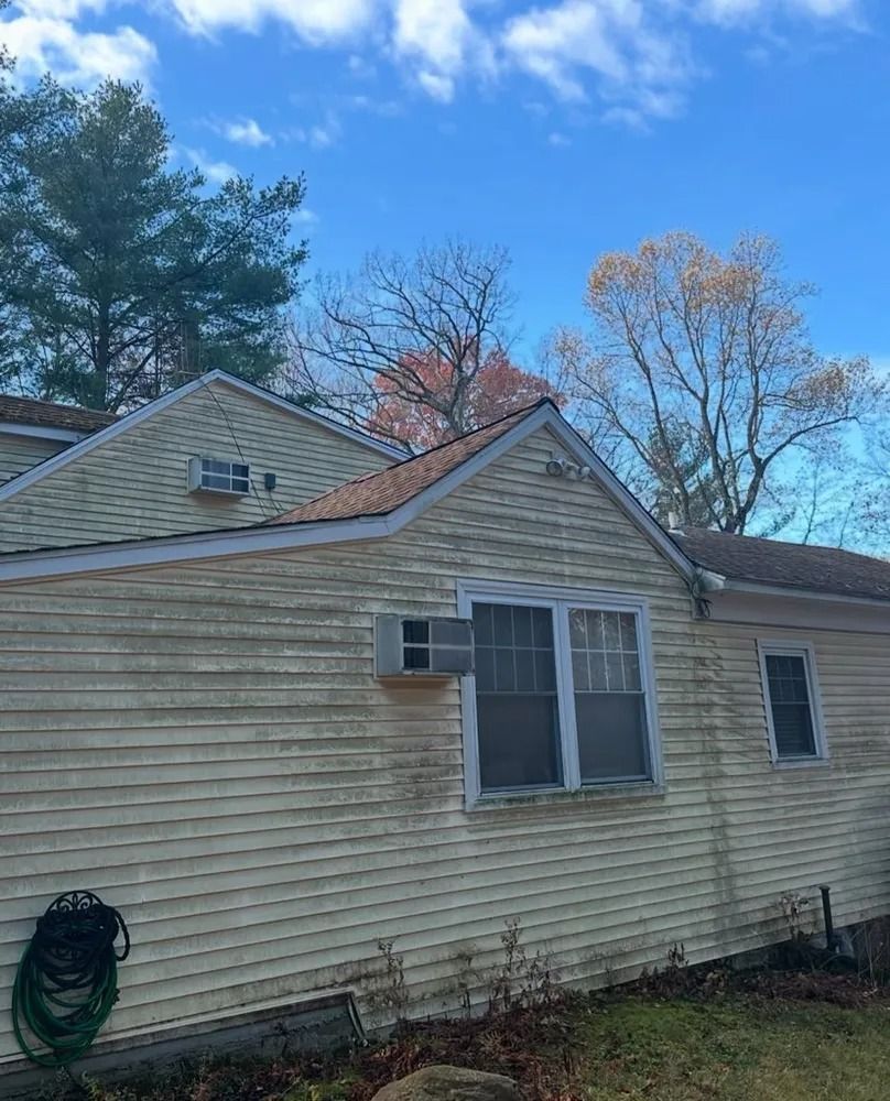 Back of a weathered, yellow house with visible algae growth. Windows are framed, and air conditioners are mounted in the walls.