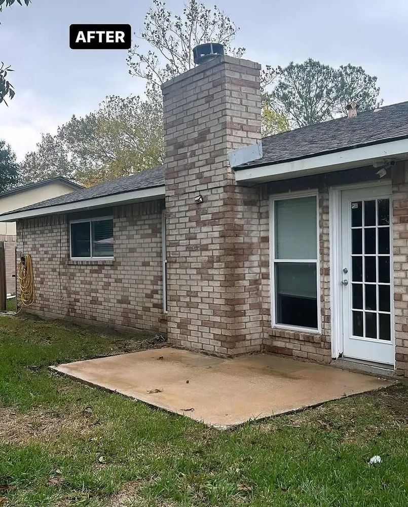 A newly renovated brick exterior of a house with a chimney and a patio, set against a backdrop of greenery and an overcast sky.