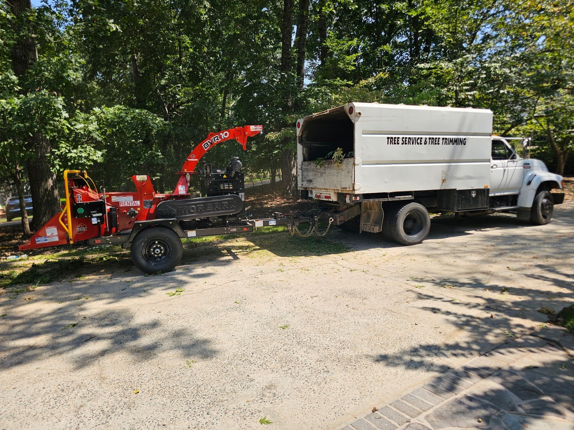 A wood chipper in operation, feeding debris into a white truck with