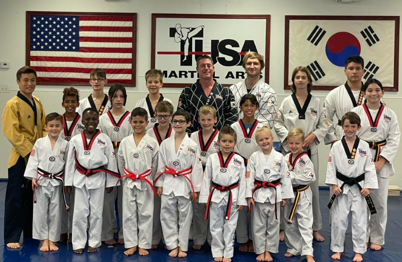 a group of young people in karate uniforms are posing for a picture .