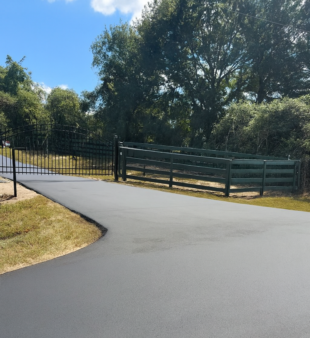Road Workers in Orange Coveralls Shoveling Asphalt onto A Freshly Paved Road — Sealy, TX — Sealy Paving, Inc.