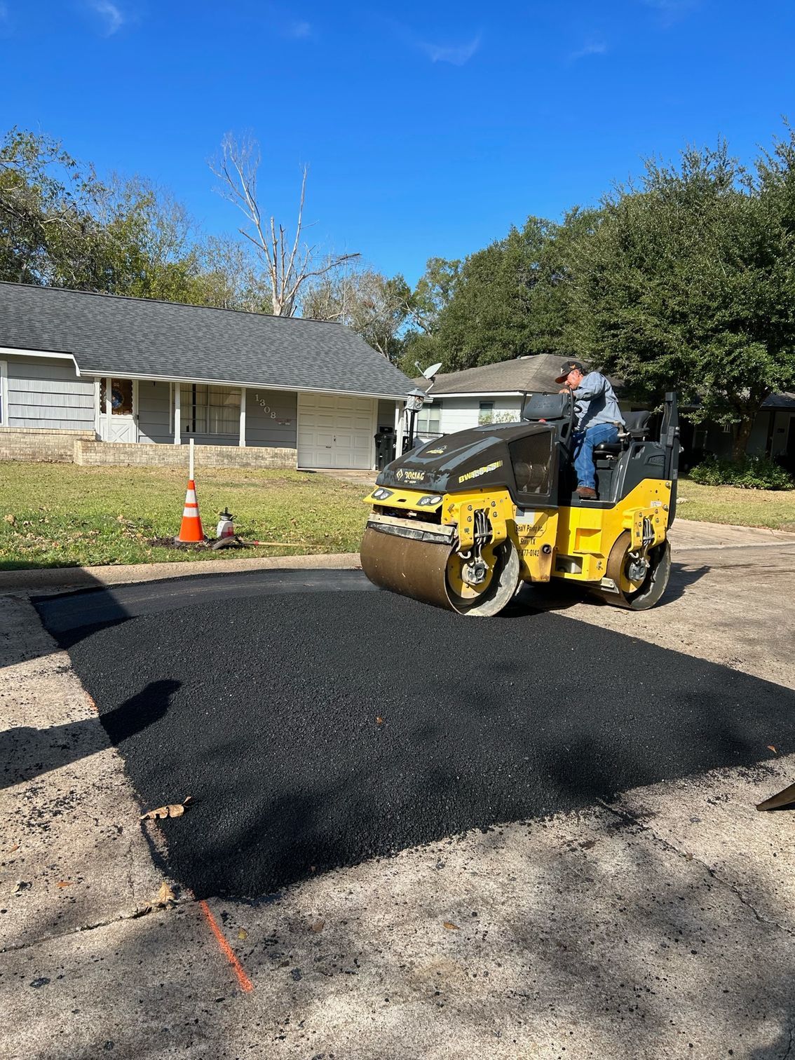 Orange Road Roller Compacting Fresh Asphalt on A Road — Sealy, TX — Sealy Paving, Inc. Orange Road Roller Compacting Fresh Asphalt on A Road — Sealy, TX — Sealy Paving, Inc.