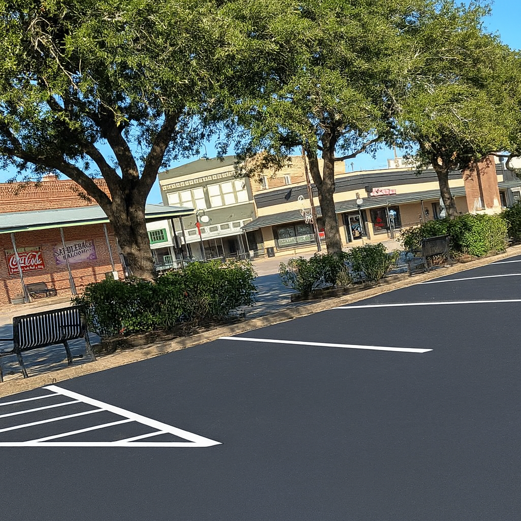 Asphalt Paving Machine Spraying Sealant onto Road Surface — Sealy, TX — Sealy Paving, Inc. Asphalt Paving Machine Spraying Sealant onto Road Surface — Sealy, TX — Sealy Paving, Inc.