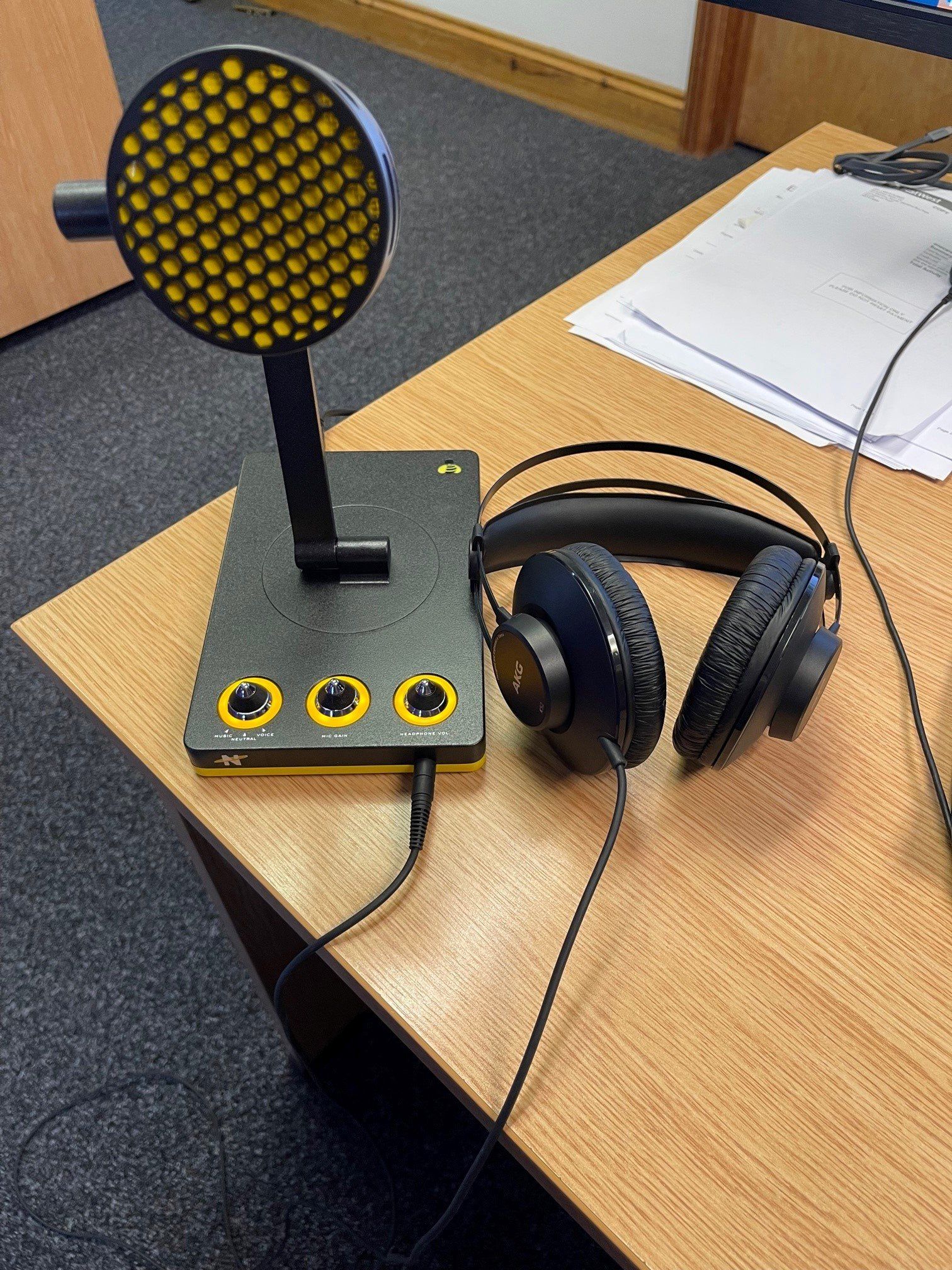 A microphone and headphones are sitting on a wooden table.