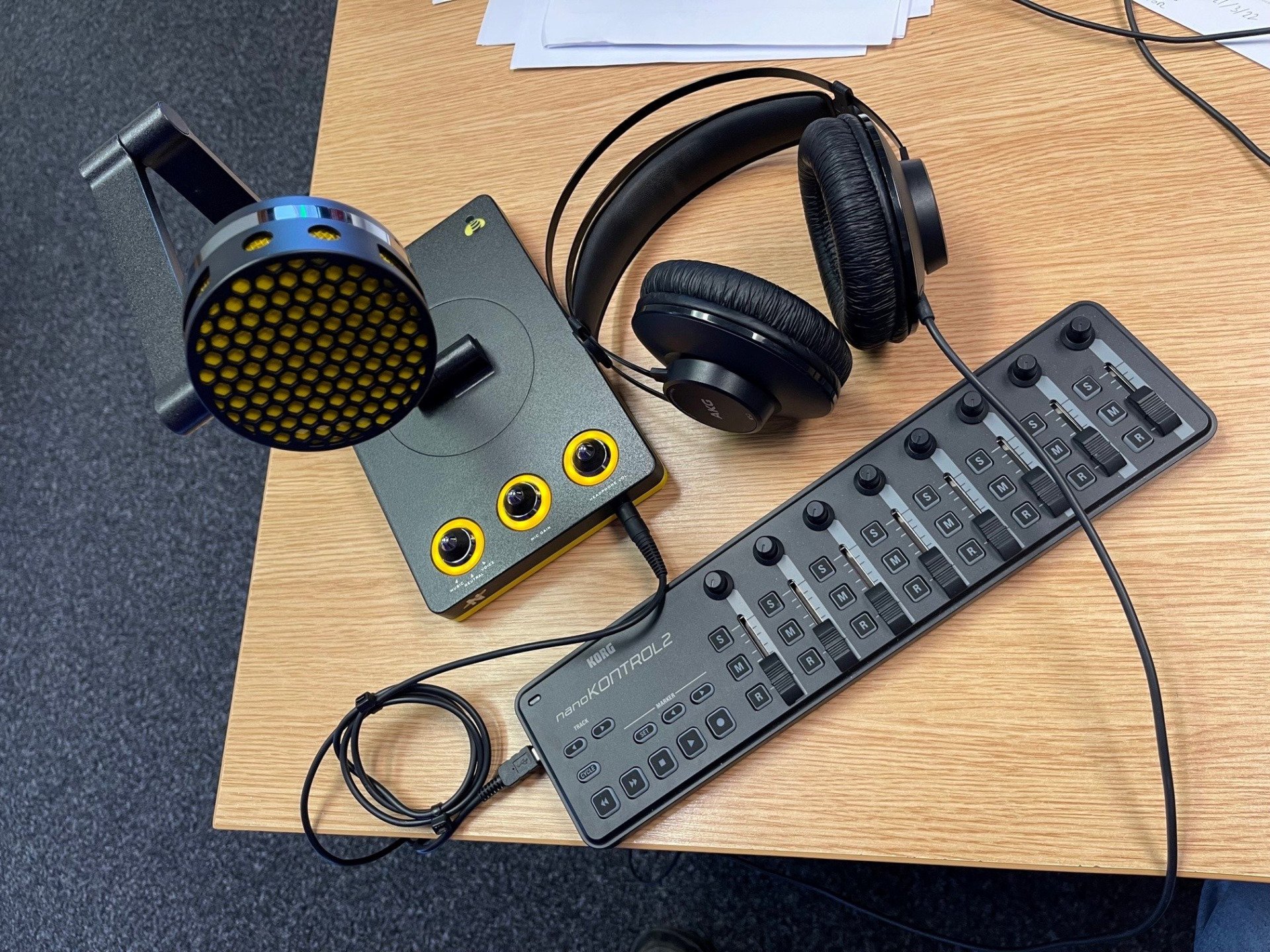 A microphone and headphones are sitting on a wooden table.