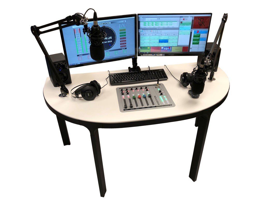 A desk with two monitors , a microphone , headphones , and a mixer.