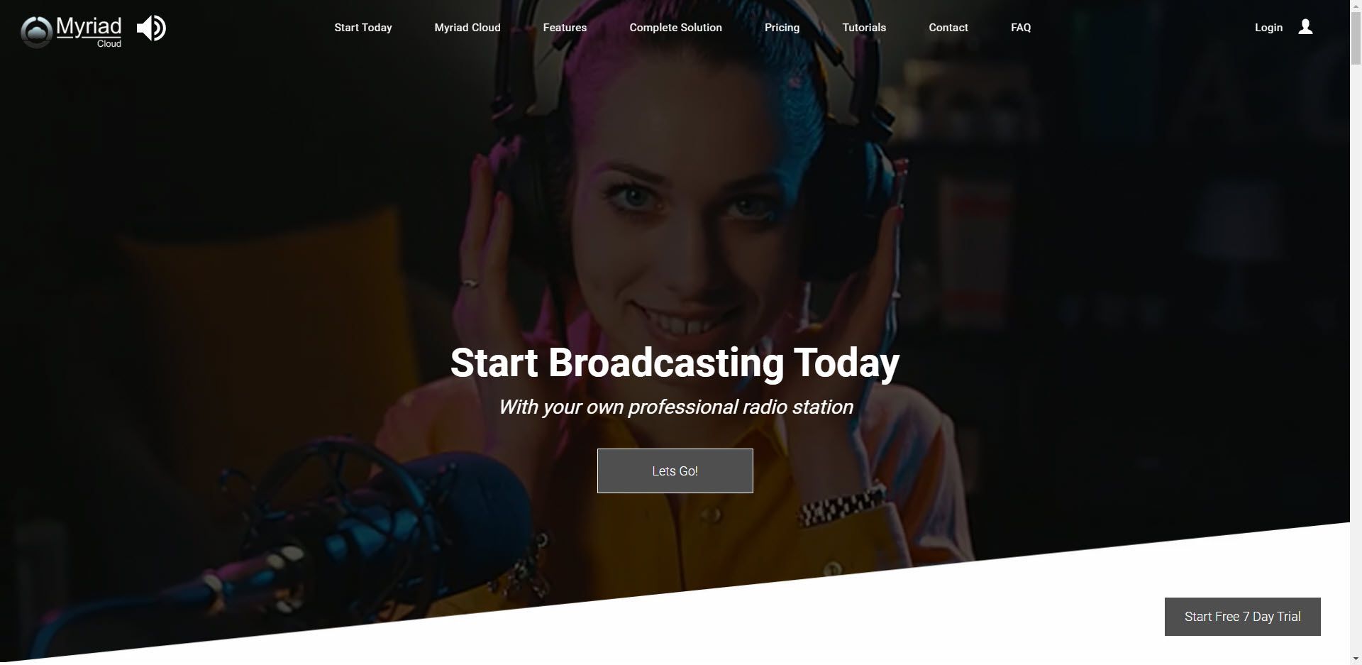 A woman wearing headphones is standing in front of a microphone.