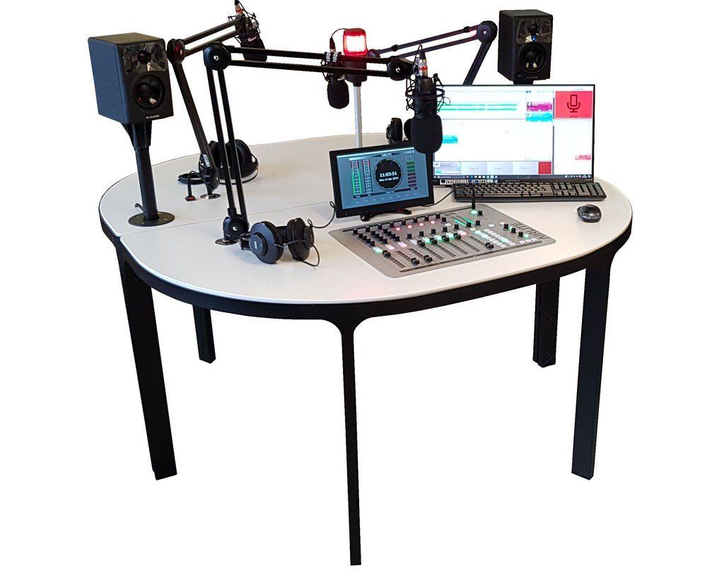 A table with a computer , microphone , speakers , and headphones on it.
