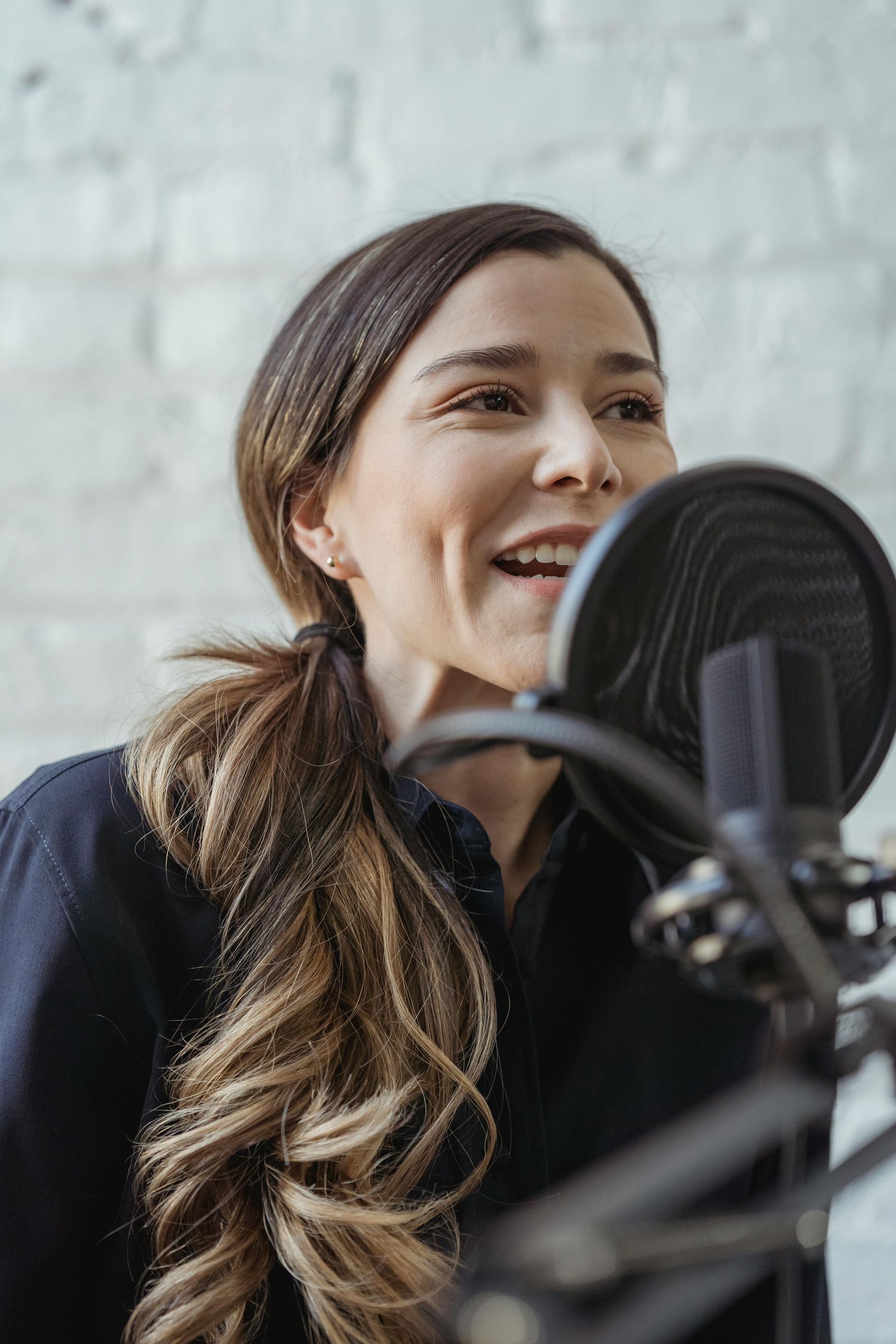 A woman is singing into a microphone and smiling.