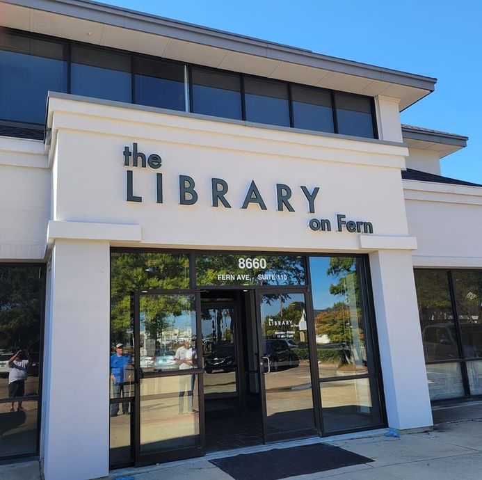 A white building with a sign that says the library on fern