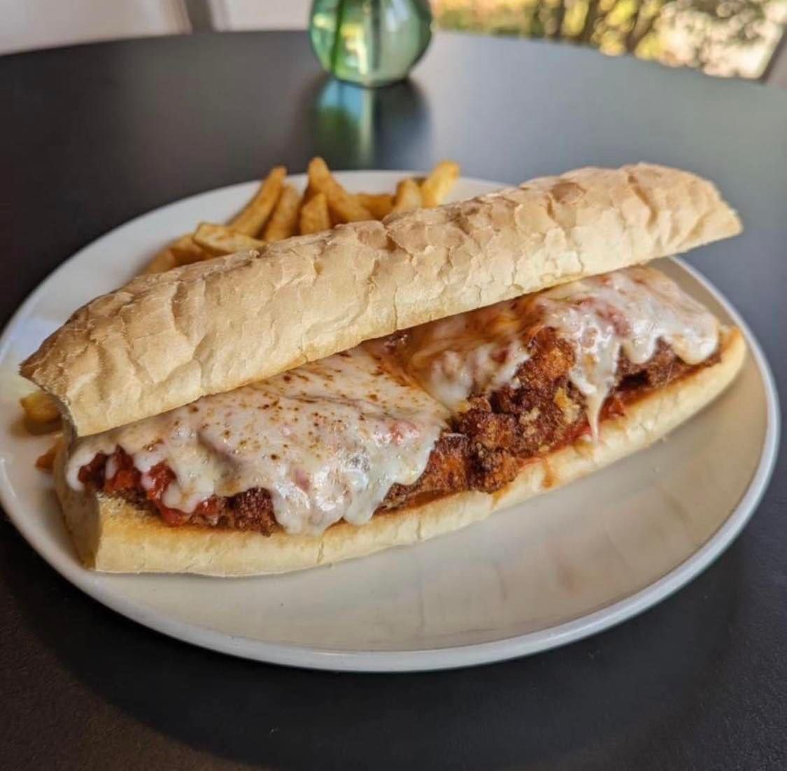 A sub sandwich on a plate with french fries