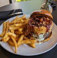 A hamburger and french fries on a white plate on a table.