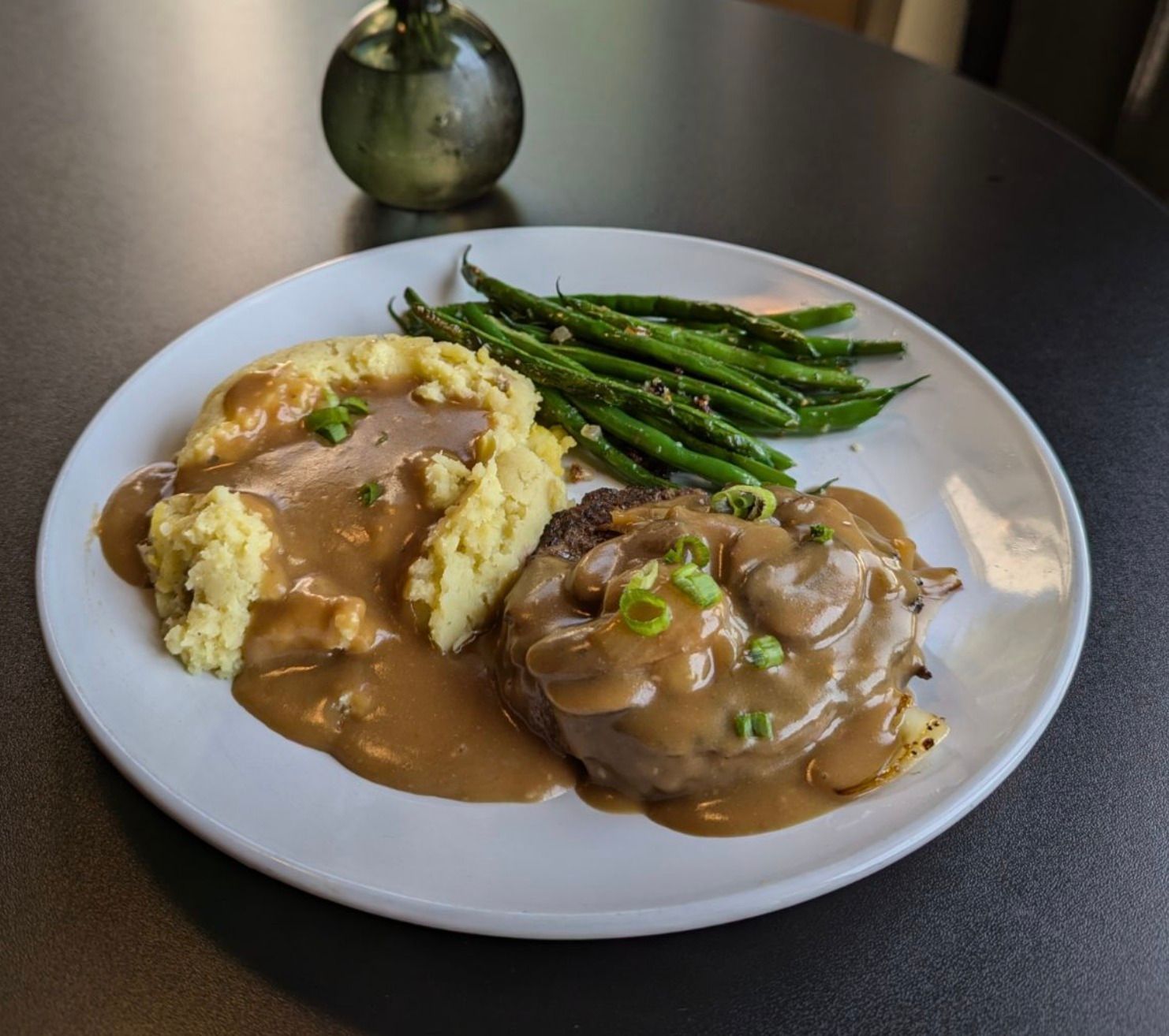 A plate of food with mashed potatoes and green beans on a table.