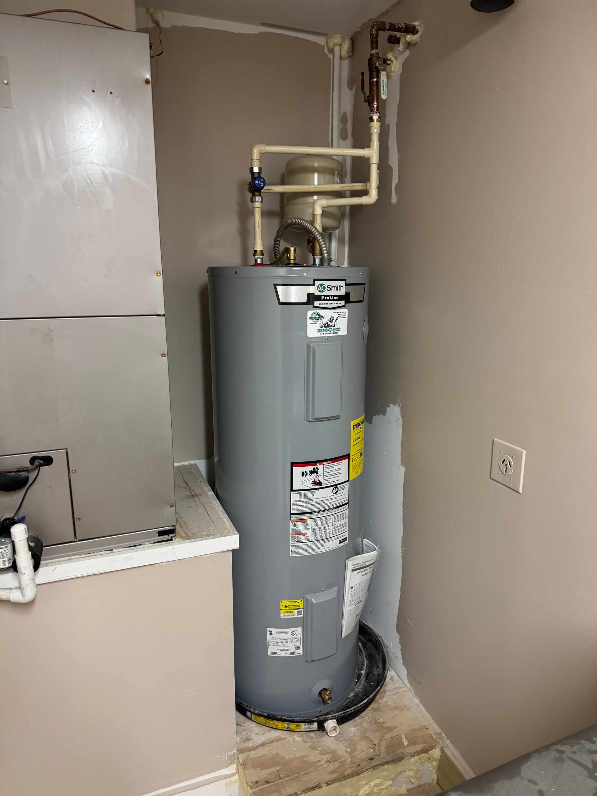 A water heater is sitting in a corner of a room next to a wall.