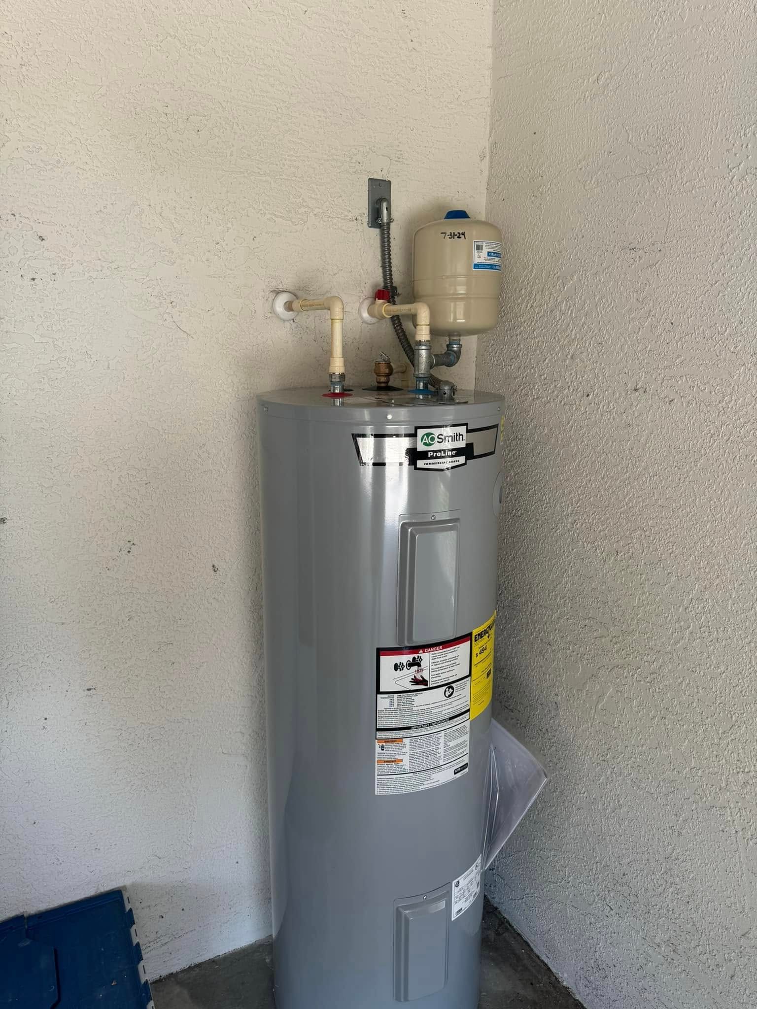A water heater is sitting in a corner of a room next to a wall.
