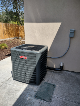 A row of air conditioners are sitting outside of a brick building.