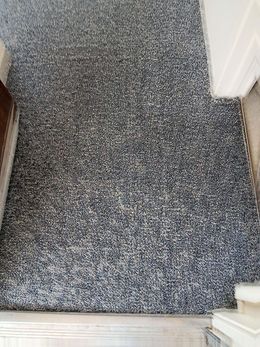 A gray carpet is sitting on the floor next to a door.