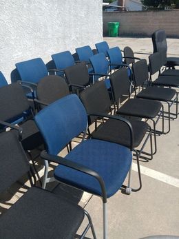 A row of blue and black chairs are lined up in a parking lot