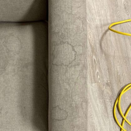 A close up of a couch with stains on it and a yellow cord.