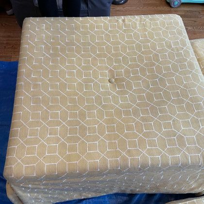 A square cushion with a pattern on it is sitting on a blue cloth.