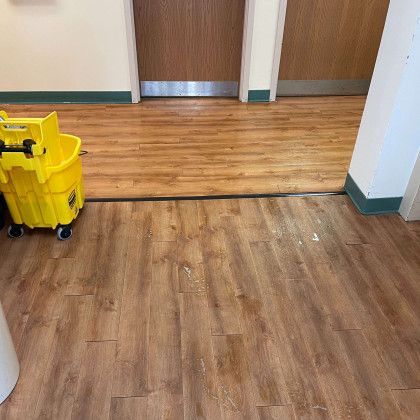 A yellow mop is sitting on a wooden floor next to a door.