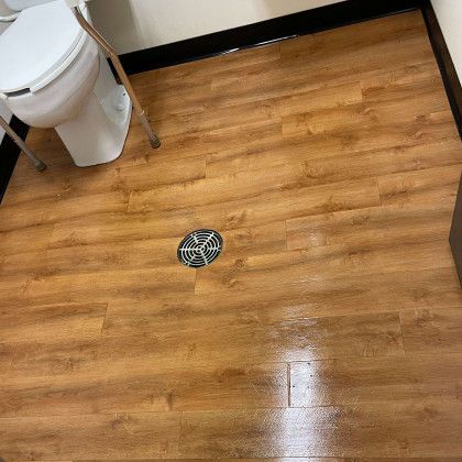 A bathroom with a toilet and a wooden floor.