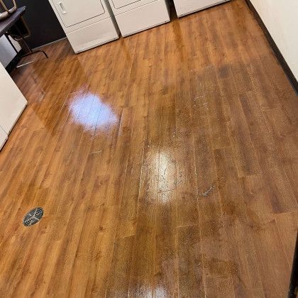 A wooden floor in a laundry room with a washer and dryer.