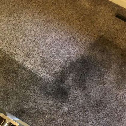 A close up of a dirty carpet with a stain on it.