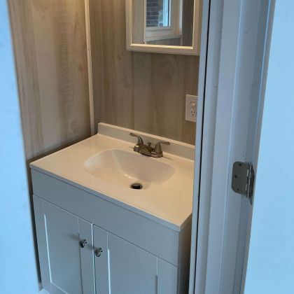 A bathroom with a sink , mirror and cabinets.