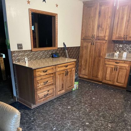A kitchen with wooden cabinets , granite counter tops , and a mirror.