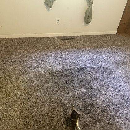 A room with a dirty carpet and a vacuum cleaner on the floor.