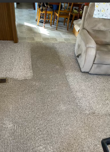 A living room with a dining room table and chairs and a recliner.