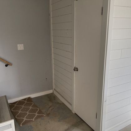 There is a rug on the floor in the hallway between the stairs and the door.