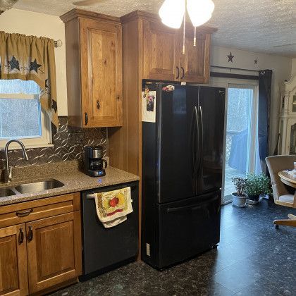 A kitchen with a black refrigerator and wooden cabinets