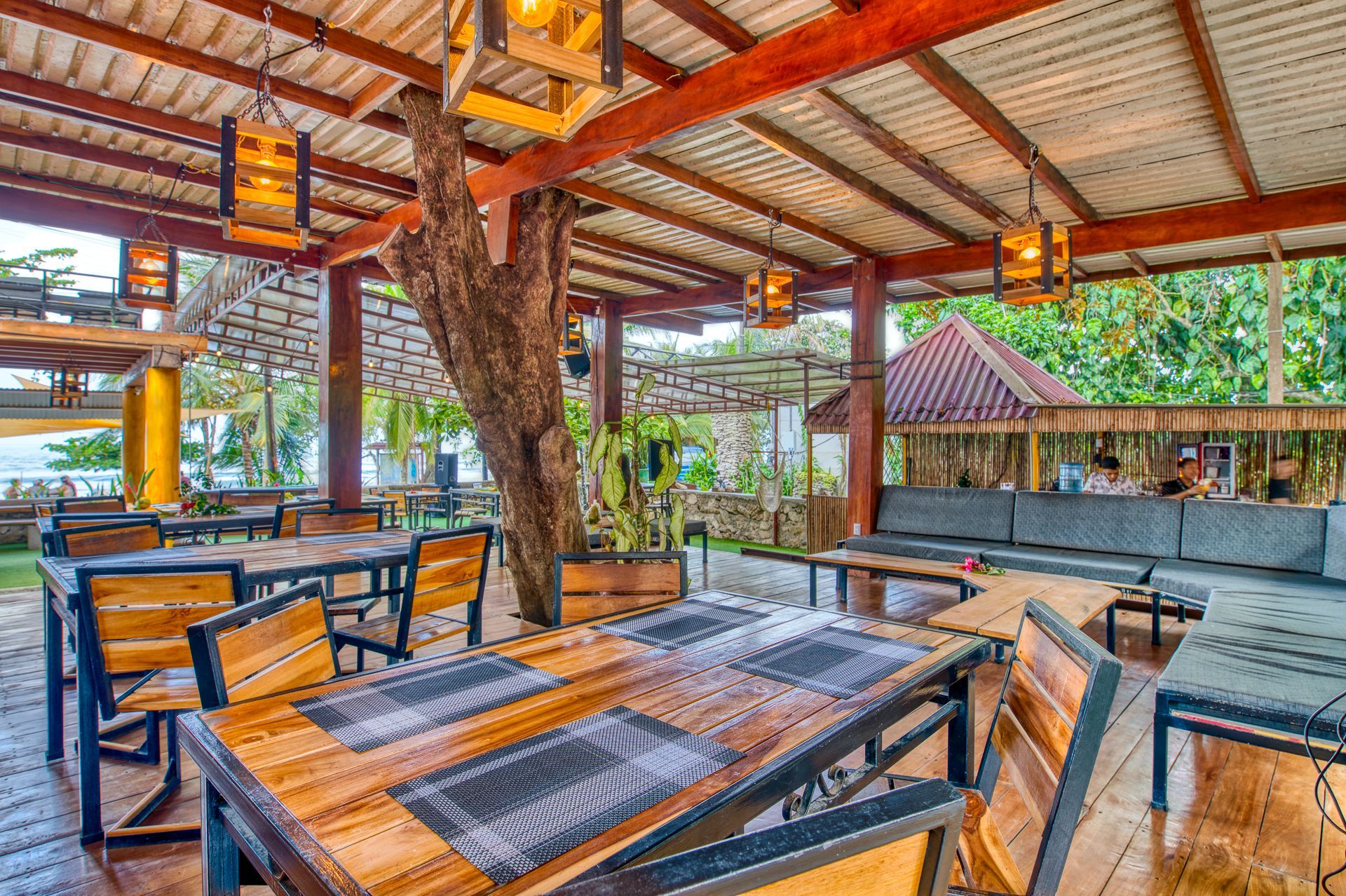A restaurant with wooden tables and chairs under a canopy.