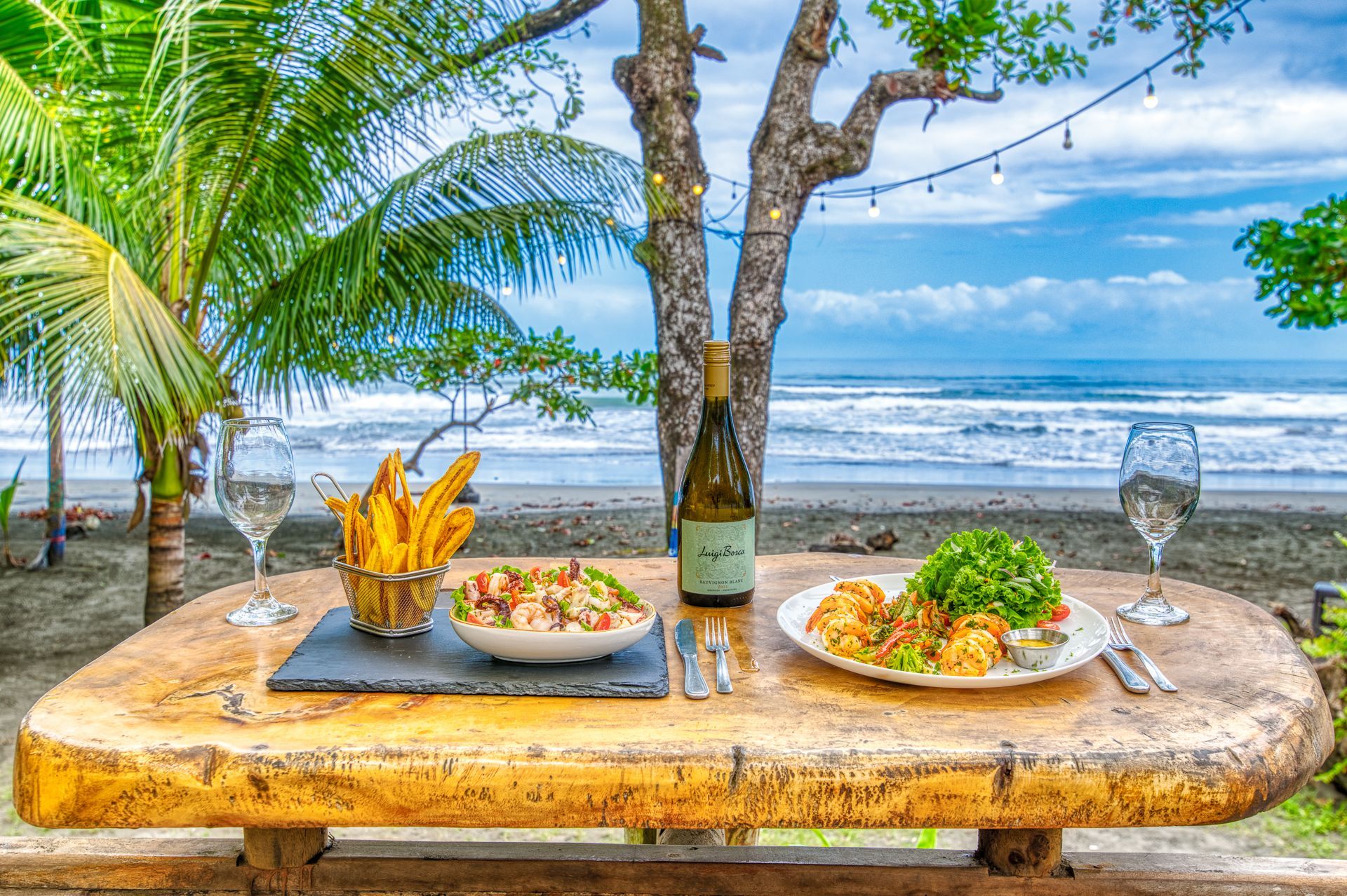A wooden table with plates of food and a bottle of wine on it.