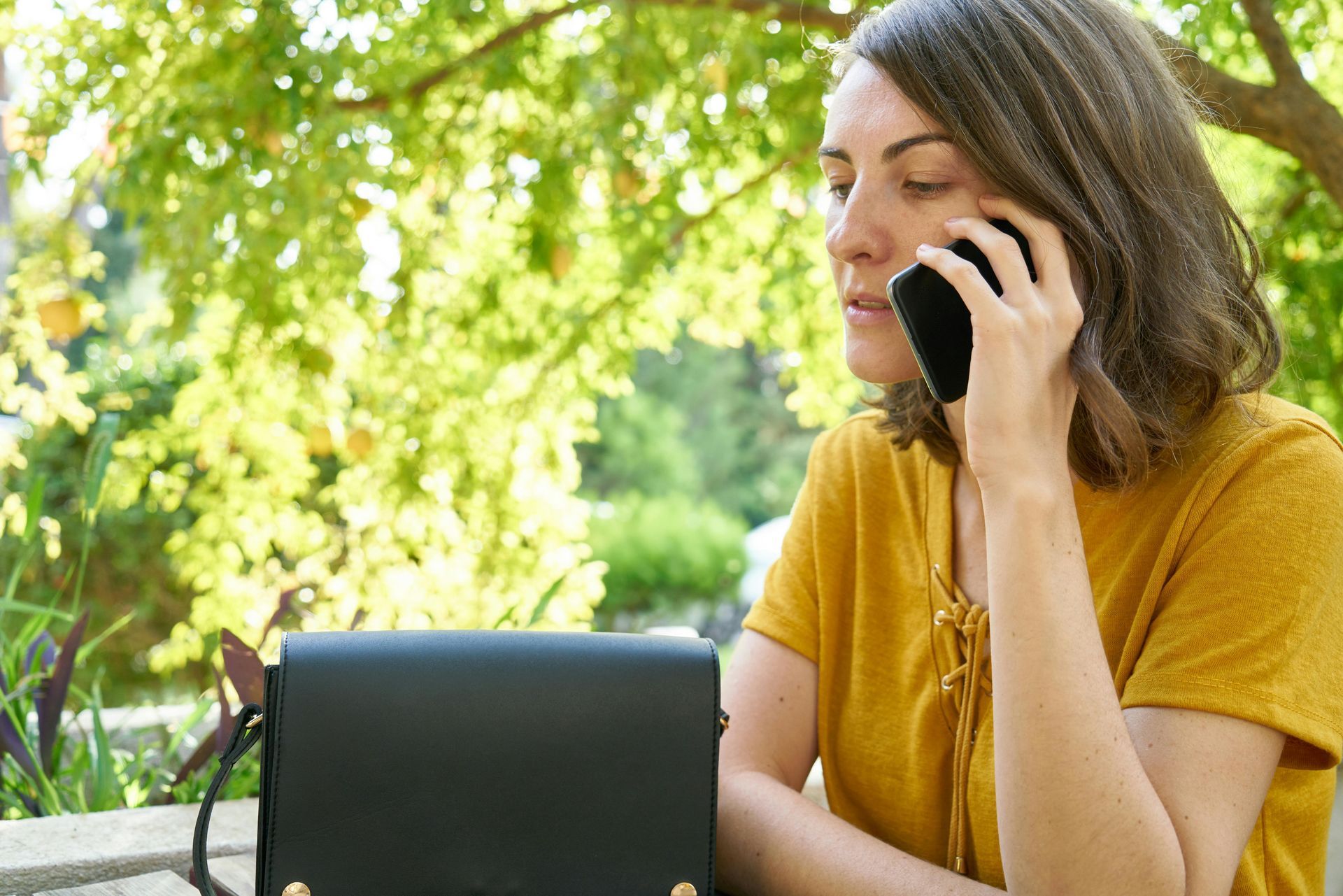 A woman is sitting at a table talking on a cell phone.