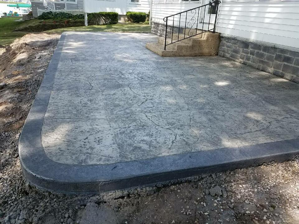 A concrete patio with stairs and a railing in front of a house