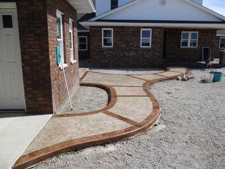A brick house with a unique concrete walkway in front of it