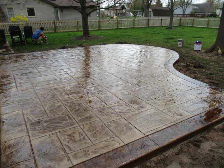 A man is sitting in a chair on a patio in a backyard
