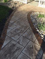 A concrete walkway leading to a gazebo in a backyard