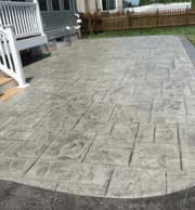 A concrete patio with a bench and a fence in the background