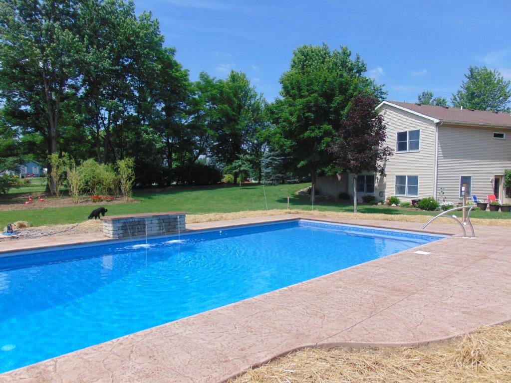 A large and clean swimming pool with a house in the background