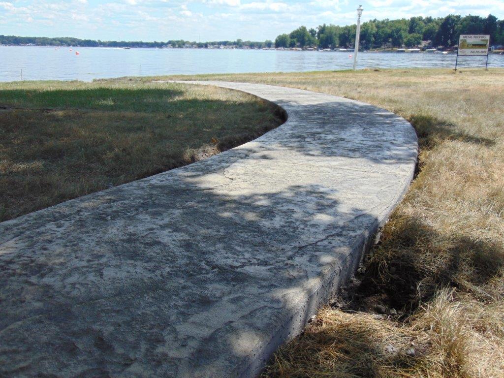 A curved concrete walkway leading to a lake
