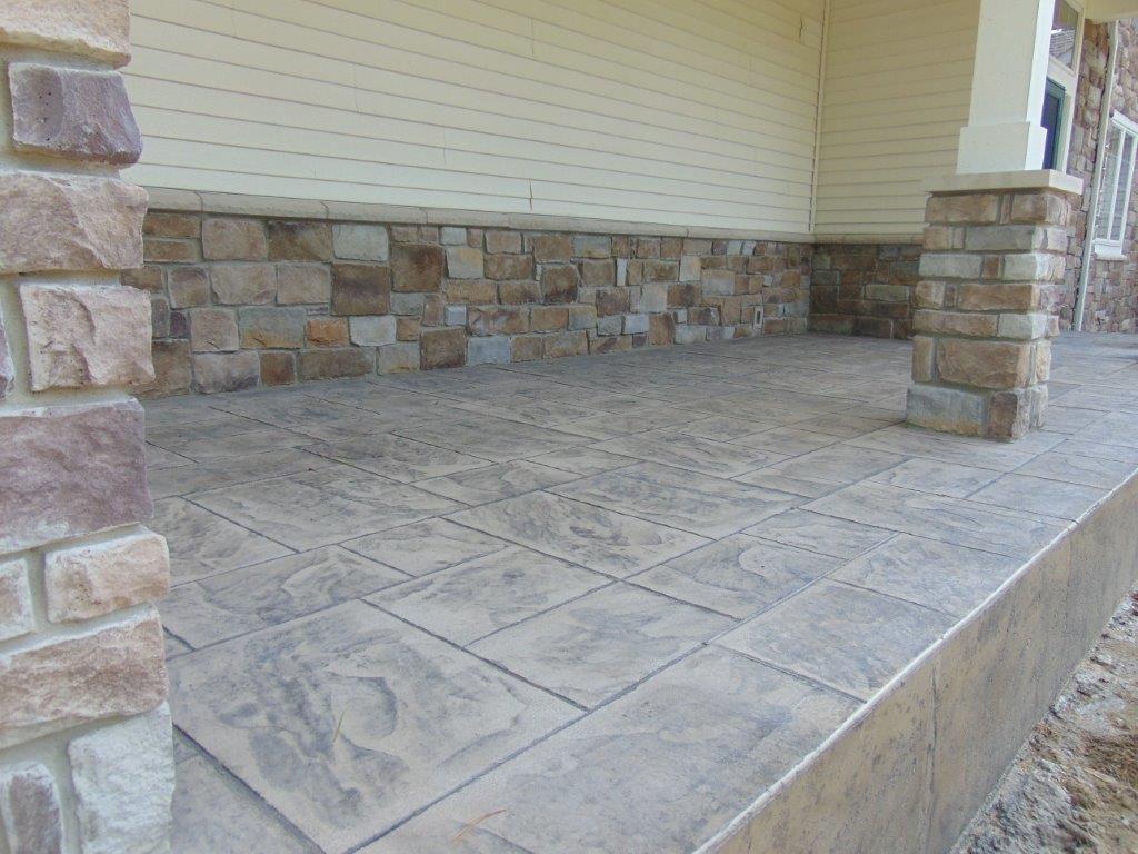 A porch with a brick wall and a concrete floor