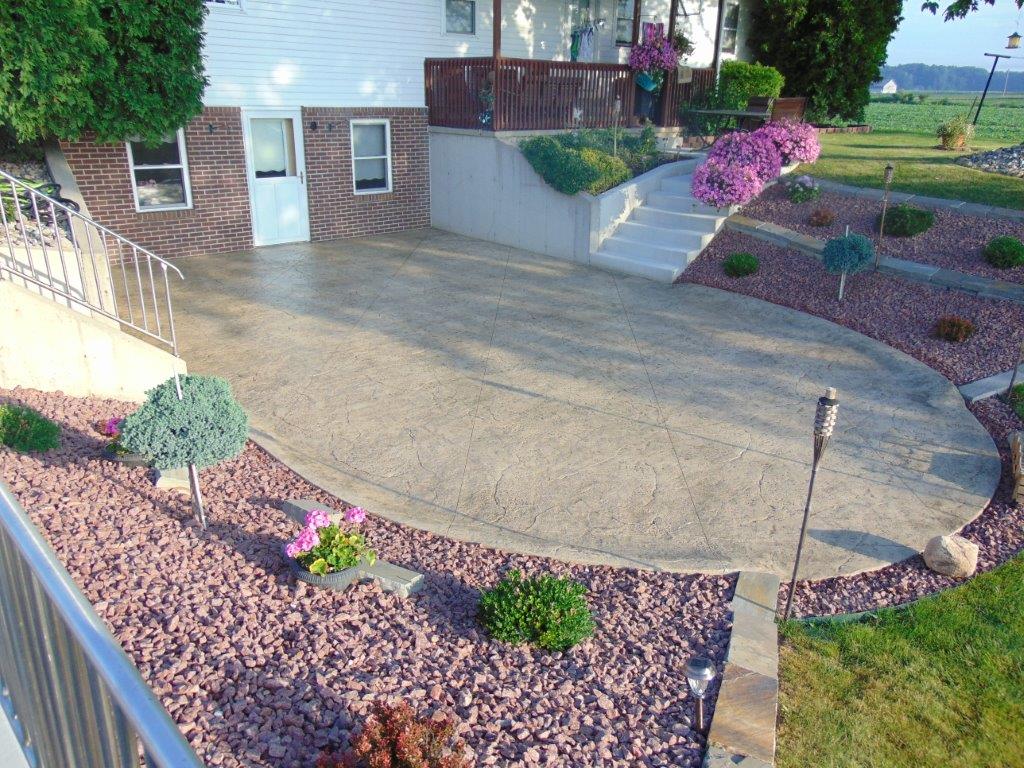 A house with a concrete driveway surrounded by gravel and flowers