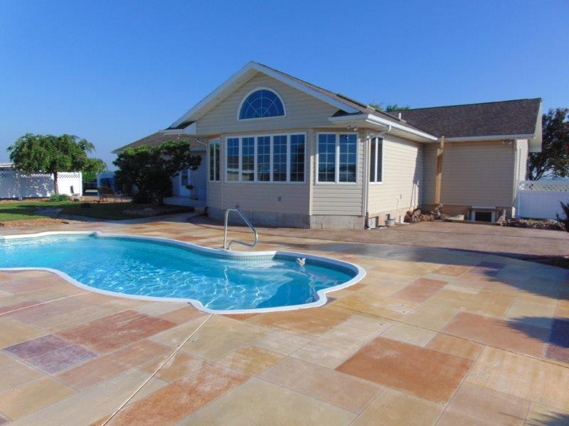 A house with a large swimming pool and a patterned patio